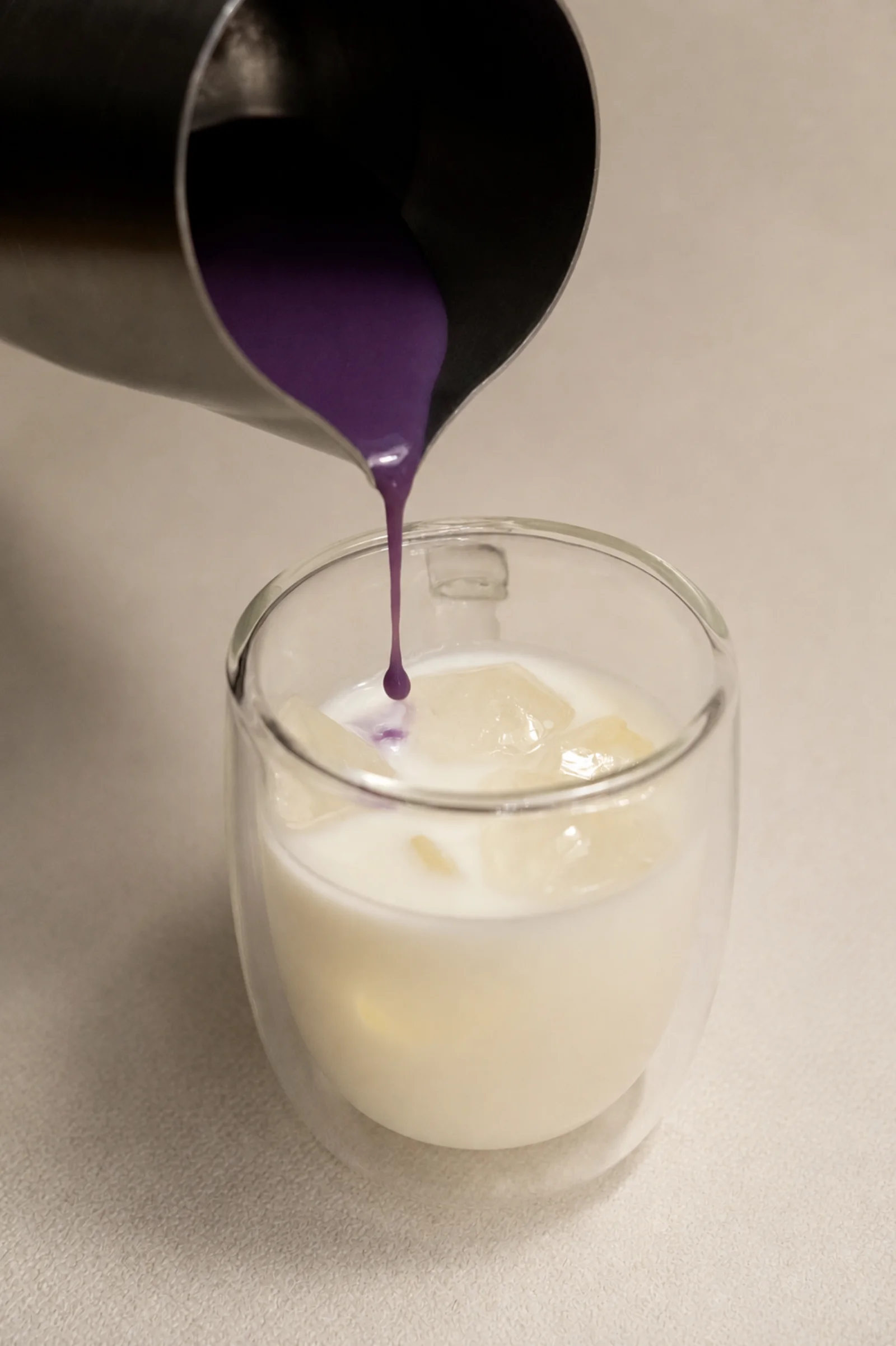 Ube syrup pouring into cold milk, showing the mellow vanilla and coconut character of real ube