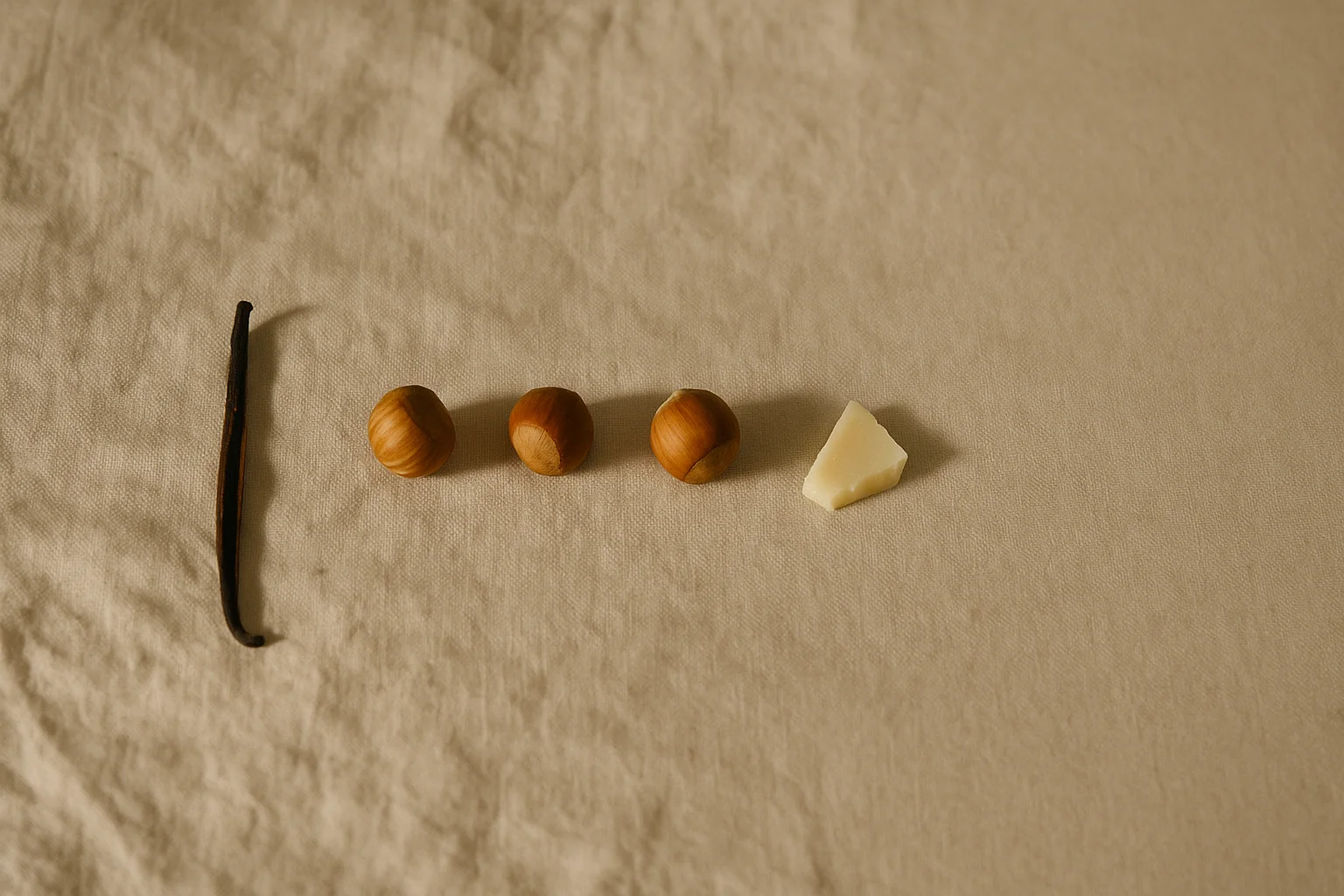 Editorial still life of a vanilla pod, hazelnuts and white chocolate on linen: the tasting notes that describe what ube tastes like